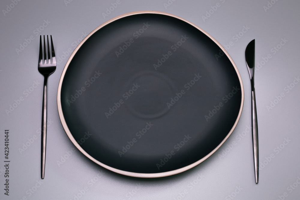 Black plate on the grey background. Copy space, top view. Black plate on the grey background. Copy space, top view.