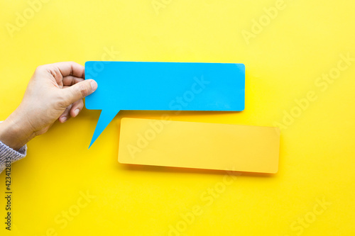 Person hand holding blank bubbles speech paper in colorful background.for ecoration text