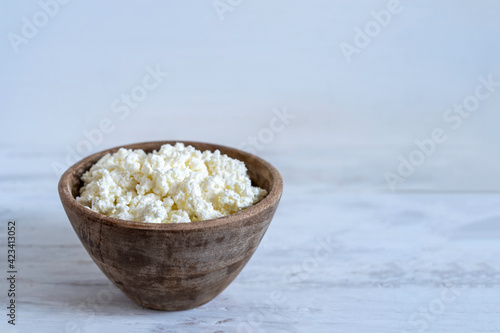 Cottage cheese in wooden bowl over white background with copy space.
