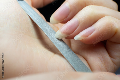 Woman makes herself a manicure at home, cuts her nails. Close-up. Nails cutting process. Nail file macro.