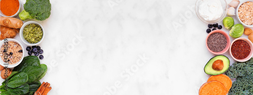 Healthy food ingredients. Above view double border on a white banner background. Copy space. Super food concept with green vegetables, berries, whole grains, seeds, spices and nutritious items.