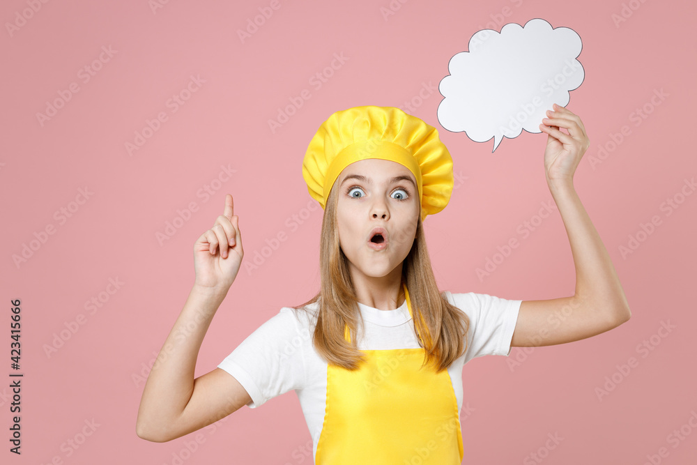 Teen girl chef cook confectioner housewife baker in yellow apron t-shirt cap hold empty blank Say cloud speech bubble for content point finger with idea isolated on pink background Food cake concept. Teen girl chef cook confectioner housewife baker in yellow apron t-shirt cap hold empty blank Say cloud speech bubble for content point finger with idea isolated on pink background Food cake concept.