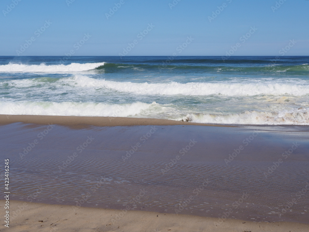 Beach landscape in the Atlantic ocean, with white waves in the water