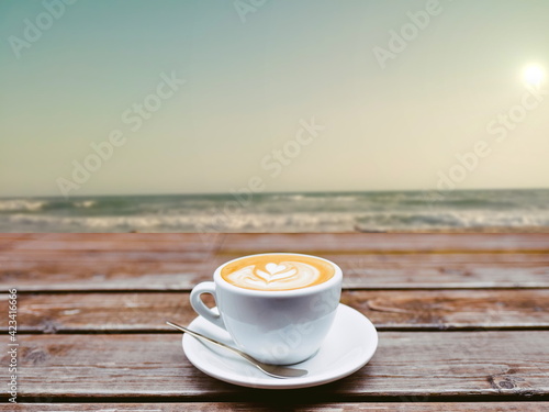 nice mornig cup of coffee on old wood table with blue sea photo