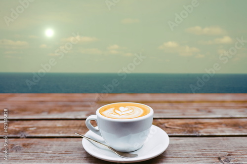 cup of coffee on old wood table with blue sea