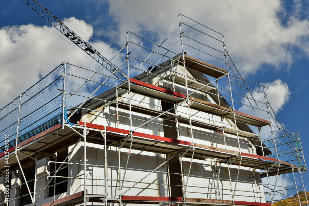 Gerüst an einem neu gebauten Mehrfamilien-Wohnhaus im Rohbau in einem Neubaugebiet Gerüst an einem neu gebauten Mehrfamilien-Wohnhaus im Rohbau in einem Neubaugebiet
