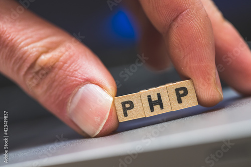 PHP programming web language: Wooden cubes with letters “PHP” lying on a laptop, concept