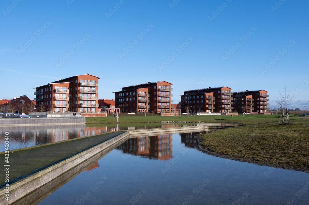 Four identical modern red brick apartment buildings standing close to a lake in Lund Sweden