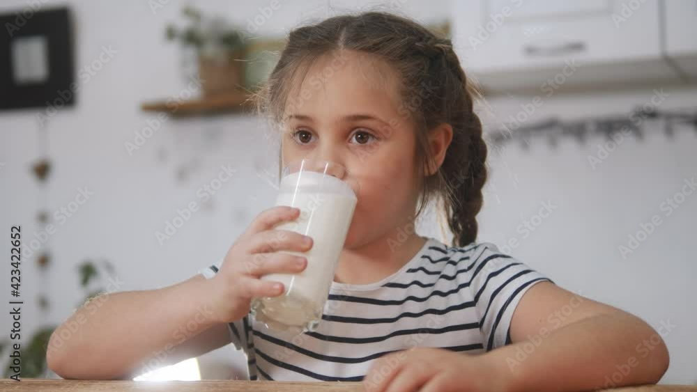 little girl child drinking milk. healthy eating a child eating breakfast kid dream concept. daughter girl in kitchen drinks yogurt milk and licks her lips. kefir positive kid smiling having breakfast little girl child drinking milk. healthy eating a child eating breakfast kid dream concept. daughter girl in kitchen drinks yogurt milk and licks her lips. kefir positive kid smiling having breakfast