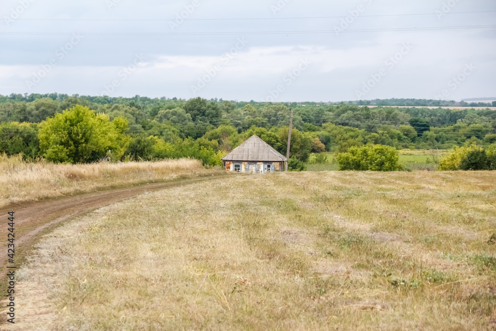 Rural landscape.  Country road, field with beveled, yellow grass and old, destroyed house in Dali.