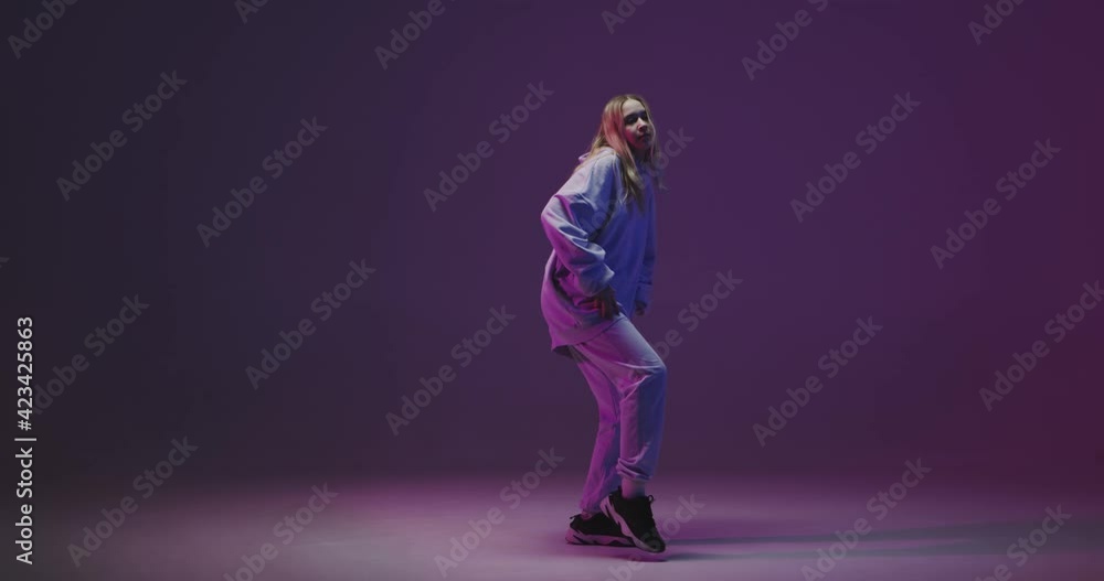 4k video of a stylish young girl, cool dancing in a hoodie hip hop dance on a neon studio background 4k video of a stylish young girl, cool dancing in a hoodie hip hop dance on a neon studio background