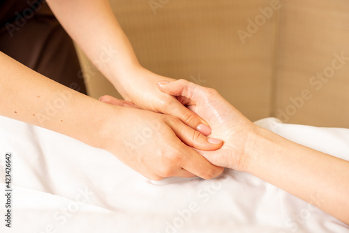 Hand massage. Physiotherapist pressing specific spots on female palm. Professional health and wellness acupressure manipulations photo