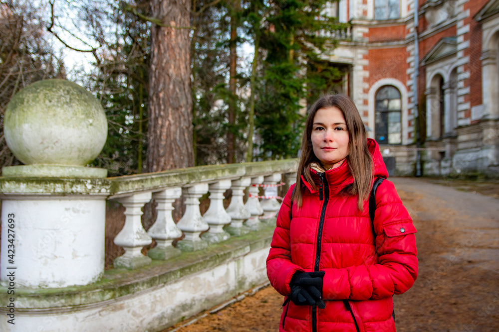 A girl in red stands next to an old manor