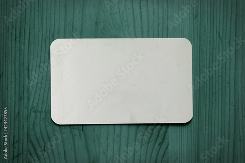 White business card template on a green wooden background.