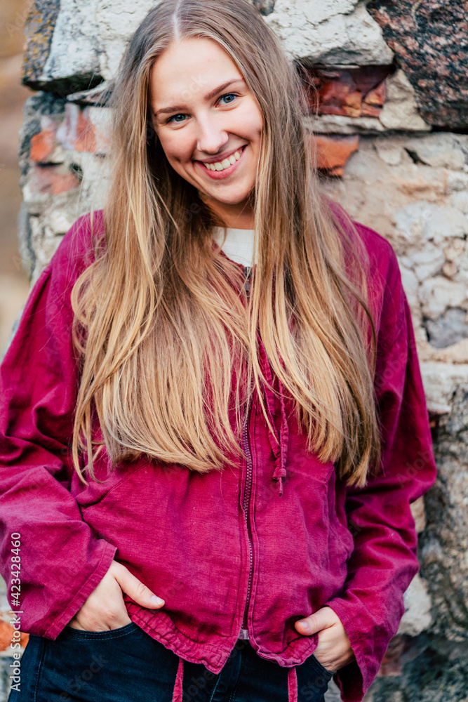 Young Caucasian Girl with Casual Smile and Brown Hair Leans Against Rock Wall Background