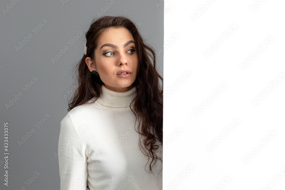 beautiful sensual woman with long curly hair shows a blank banner, isolated on gray, copy space beautiful sensual woman with long curly hair shows a blank banner, isolated on gray, copy space