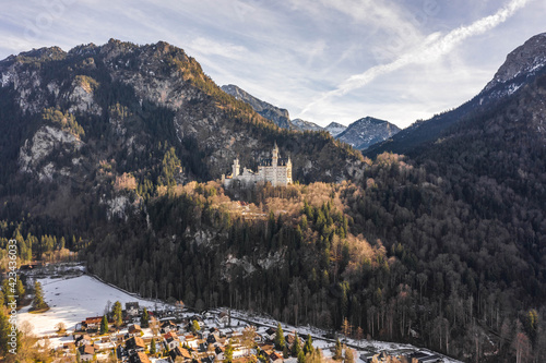 Aerial drone shot of picturesque Neuschwanstein Castle on snowy hill in winter sunlight in Germany