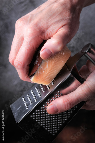 Woman grating cheese. Piece of parmesan cheese. 