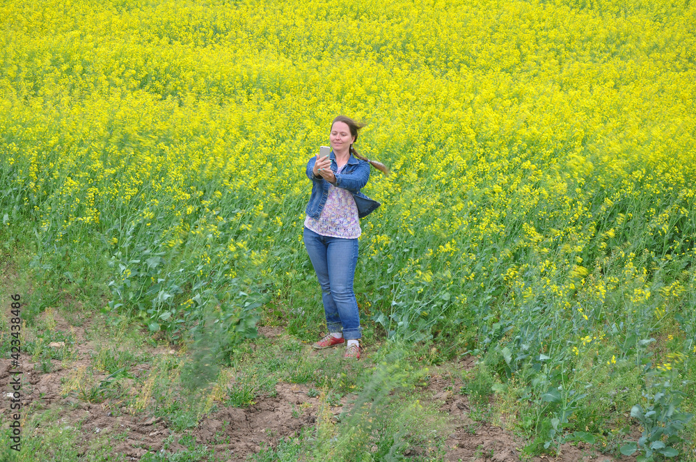 A woman takes a selfie at the edge of a rapeseed field. Russia