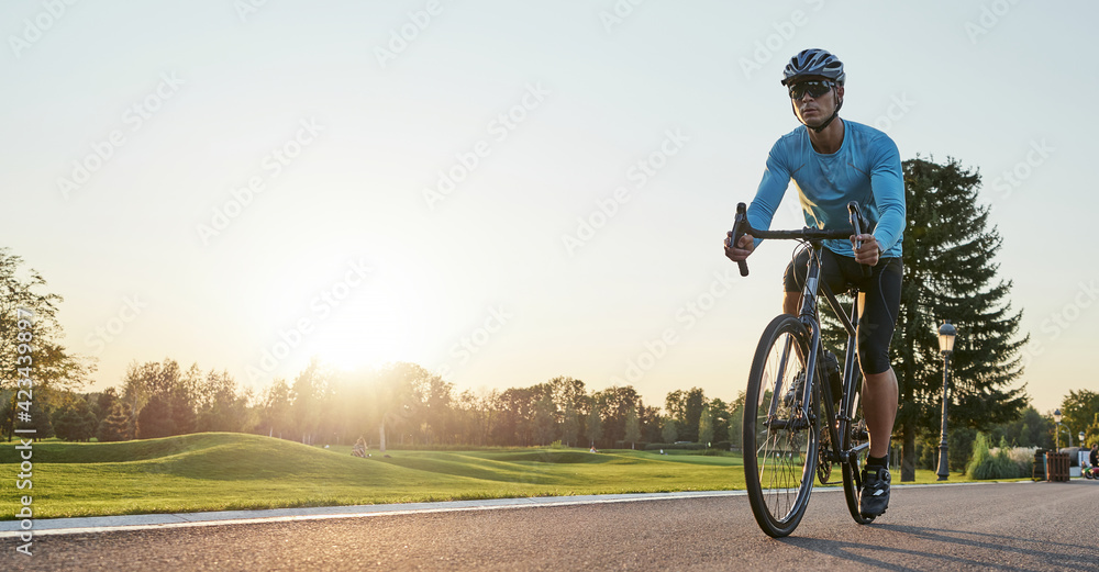 Obraz premium Website header of Rear view of athletic man in sportswear standing with bicycle on the road. Riding mountain road bike on a sunny summer day
