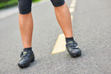 Close up shot of legs of professional male cyclist wearing cycling shoes, standing on the road outdoors