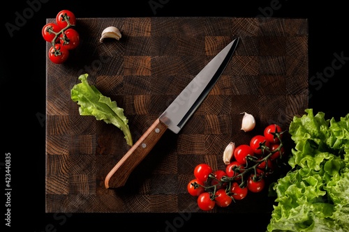 Handmade wooden chopping board with fresh vegetables on a dark background. space for labels