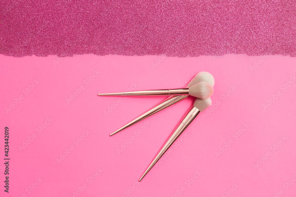 top view of make-up brushes of different sizes on a pink sparkles background top view of make-up brushes of different sizes on a pink sparkles background