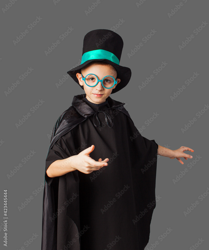 Young magician performing a trick. Little boy wearing top-hat and black magician cloak.