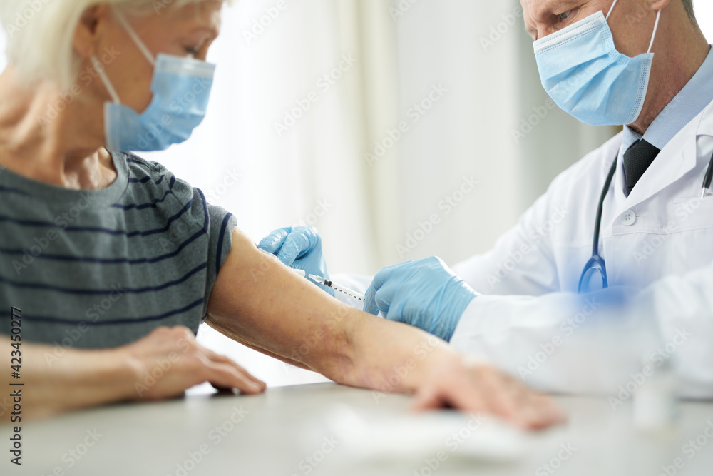 Obraz premium Doctor in sterile gloves injecting vaccine into patient arm