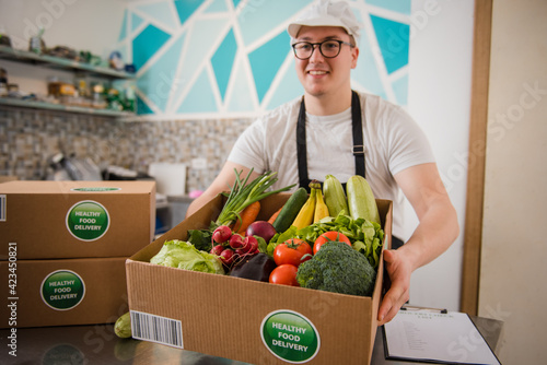 Man holding cardboard full of fresh vegetables