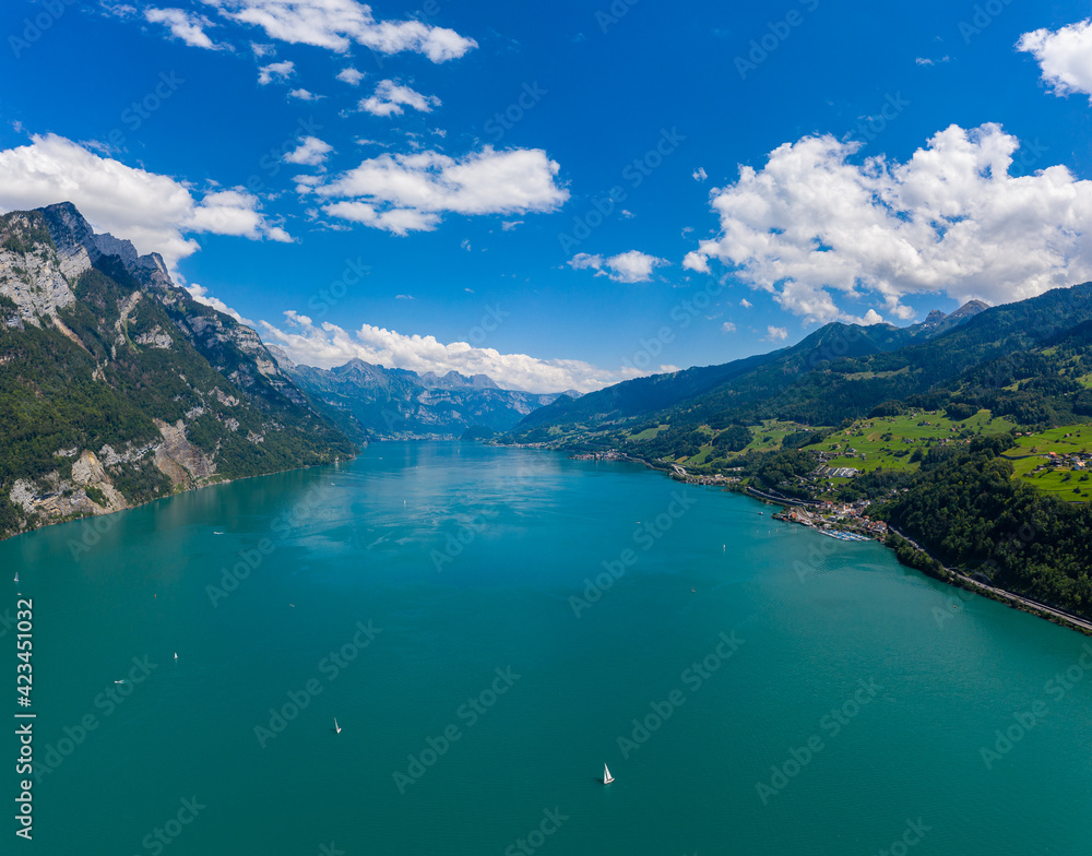 Aerial drone shot over beautiful Walensee  lake, Switzerland, with boats and yacht sailing through turquoise waters 