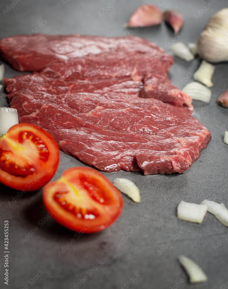 Fresh raw steak meat on a stone slate.