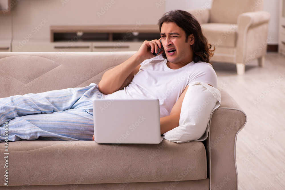 Young lazy man in oversleeping concept at home Young lazy man in oversleeping concept at home