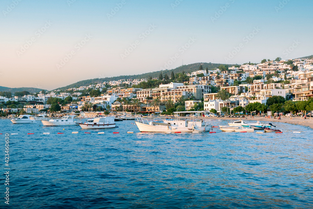 Beautiful view of Bodrum beach, sailboats, yachts and hotels at sunset. Summer holidays concept.