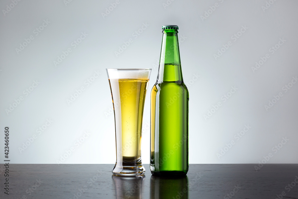 Glass and bottle of fresh beer on grey background. Non alcoholic beer. Glass and bottle of fresh beer on grey background. Non alcoholic beer.