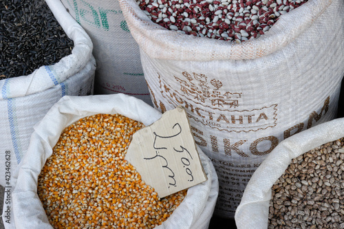 Dried corn and various kinds of dried beans are sold by weight from bags at the Dezerters' Bazaar open-air market in Tbilisi, Georgia, with prices written in Georgian script. photo