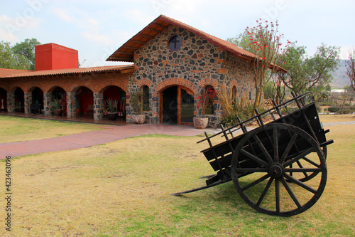 Hacienda colonnial country house, stone construction arches and wooden cart on the lawn photo