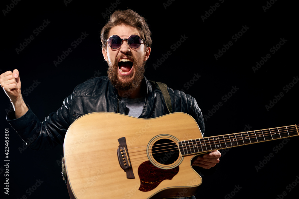 Obraz premium A man with a guitar in his hands leather jacket music performance rock star modern style dark background