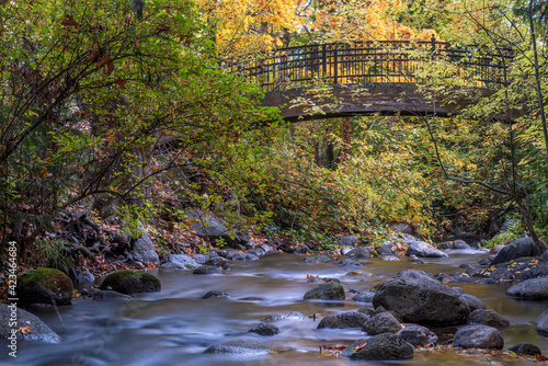 Bridge at Lithia Park in Ashland, Oregon, by the creek in the Autumn, featuring yellow colors and long exposure water photo