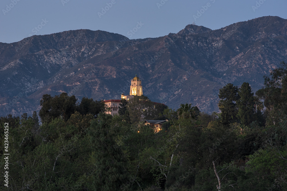 This image shows the landmark Richard Chambers Courthouse building in Pasadena towering over the trees along the Arroyo Seco. The San Gabriel Mountains are in the background.