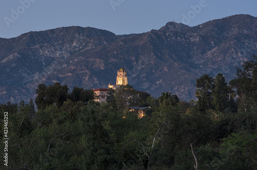 This image shows the landmark Richard Chambers Courthouse building in Pasadena towering over the trees along the Arroyo Seco. The San Gabriel Mountains are in the background.