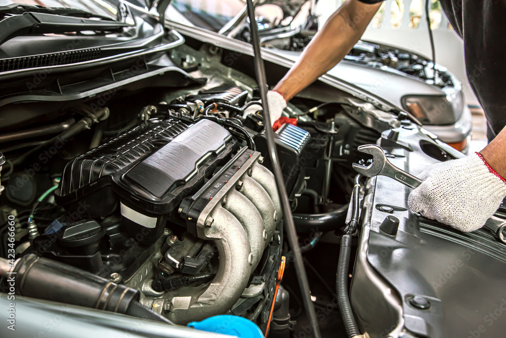 Close-up hands of auto mechanic are using the wrench to repair and maintenance auto engine is problems at car repair shop. Concepts of car care check and fixed and services insurance. Close-up hands of auto mechanic are using the wrench to repair and maintenance auto engine is problems at car repair shop. Concepts of car care check and fixed and services insurance.