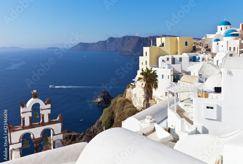 Greece. Santorini island. The beautiful village of Oia with white Cycladic houses with round roofs and a traditional arched bell tower on a sunny day. Narrow streets without tourists