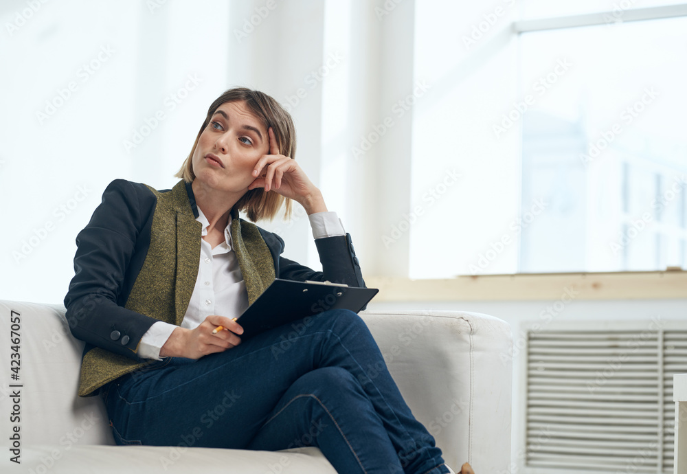 Business woman in suit with documents sitting on sofa indoors Business woman in suit with documents sitting on sofa indoors