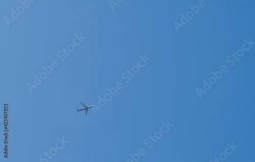 Airliner flying high above in clear blue sky.