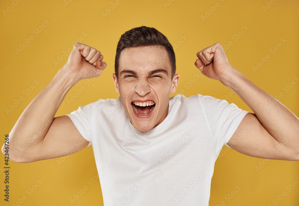 Happy guy on a yellow background gestures with his hands portrait model cropped view Happy guy on a yellow background gestures with his hands portrait model cropped view