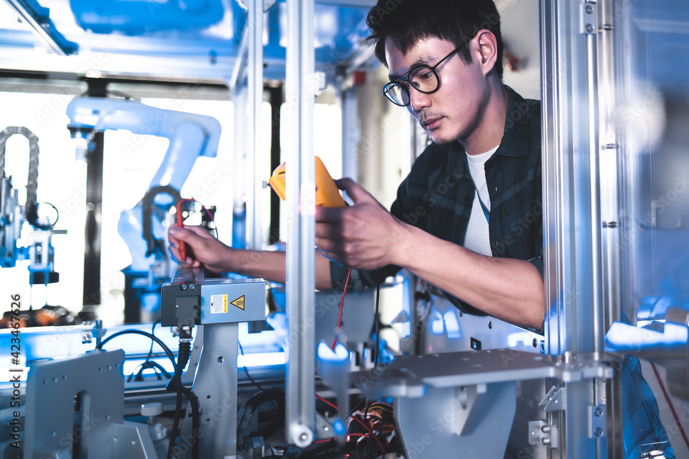 Male Engineers Maintenance Robot Arm at Lab. he are in a High Tech Research Laboratory with Modern Equipment. Technology and Innovation Concept.Professional Japanese Development Engineer is Testing .