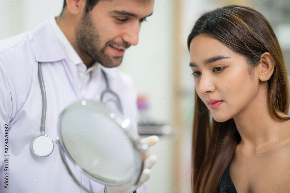 Beautician doctor wear glove and holding mirror for female in the beauty clinic. Woman looking at her face after plastic surgery. Cosmetic treatment on her facial skin. Service and enhancement. Beautician doctor wear glove and holding mirror for female in the beauty clinic. Woman looking at her face after plastic surgery. Cosmetic treatment on her facial skin. Service and enhancement.