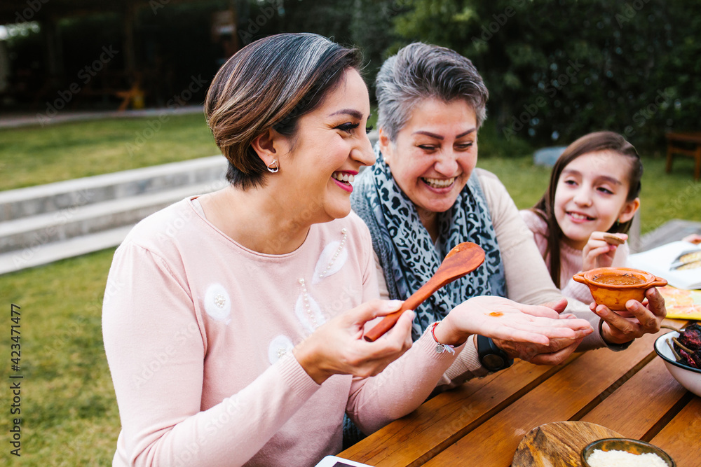 latin grandmother and granddaughter, daughter cooking mexican food at