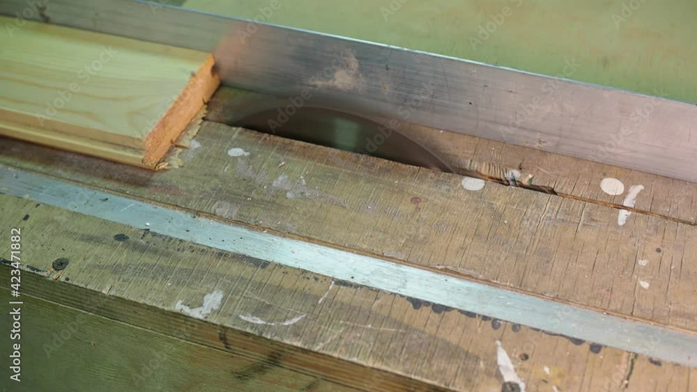 Home workshop, woodworking. The worker turns on the circular saw and saws the board. Close-up. Home workshop, woodworking. The worker turns on the circular saw and saws the board. Close-up.